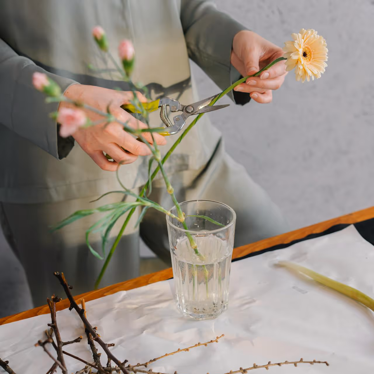  A woman arranging flowers in a glass vase.