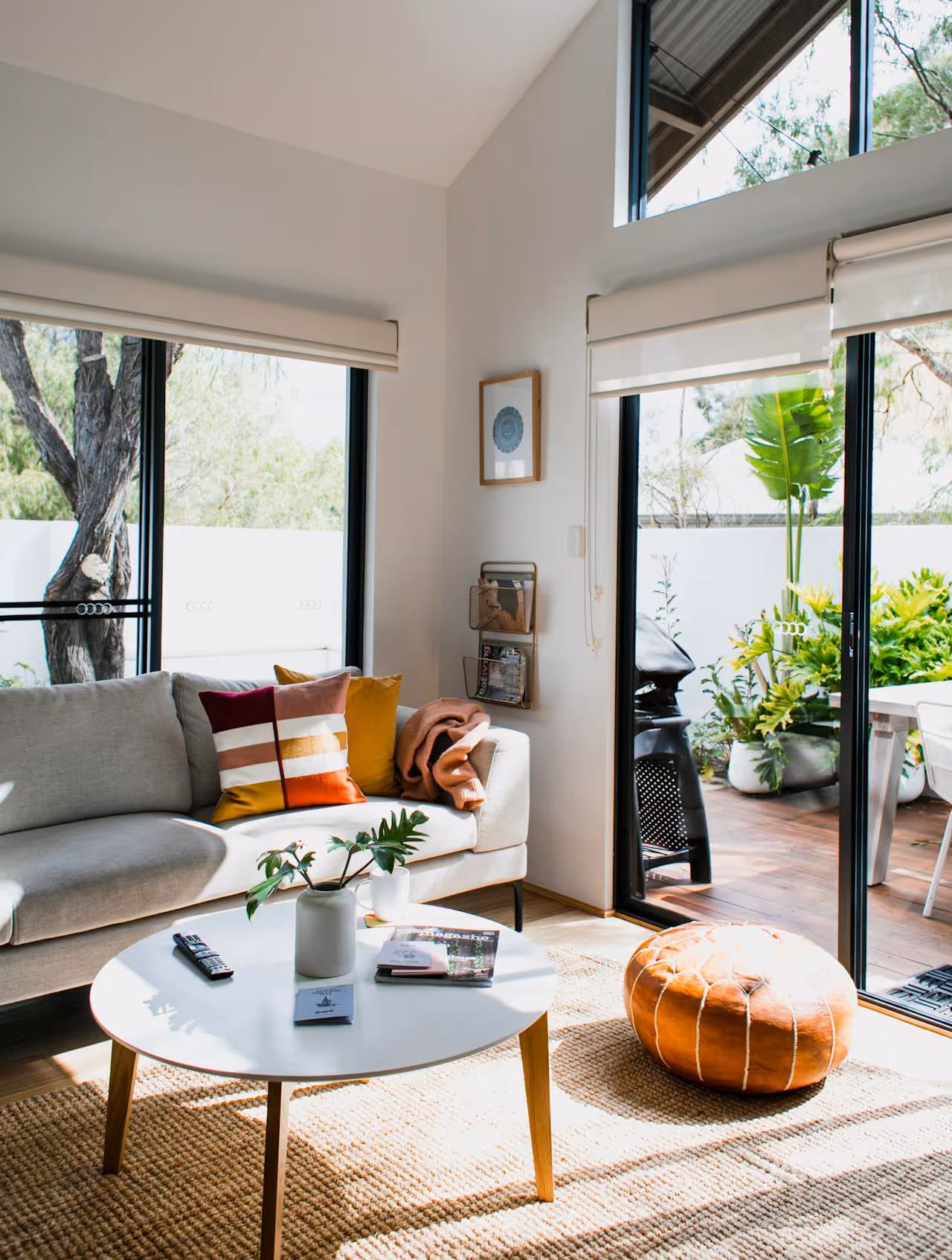 A living room with a high ceiling and an enormous glazed wall.