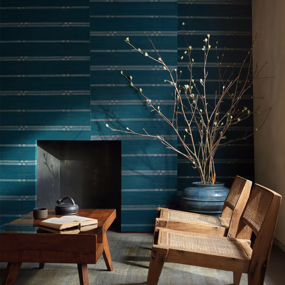 A room with one wallpapered in a dark teal grasscloth wallcovering.