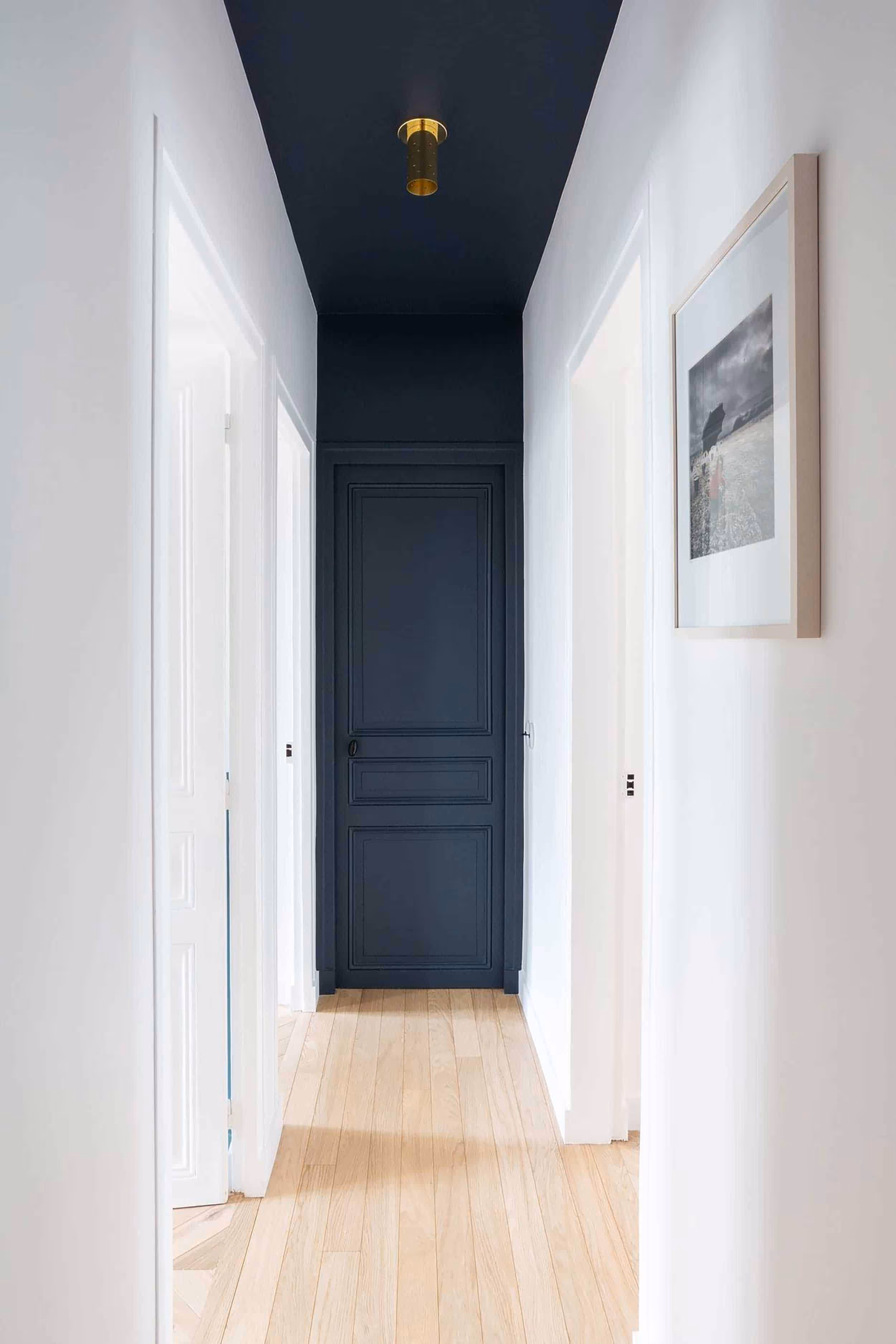 A long hallway painted white, with a dark blue end wall and ceiling