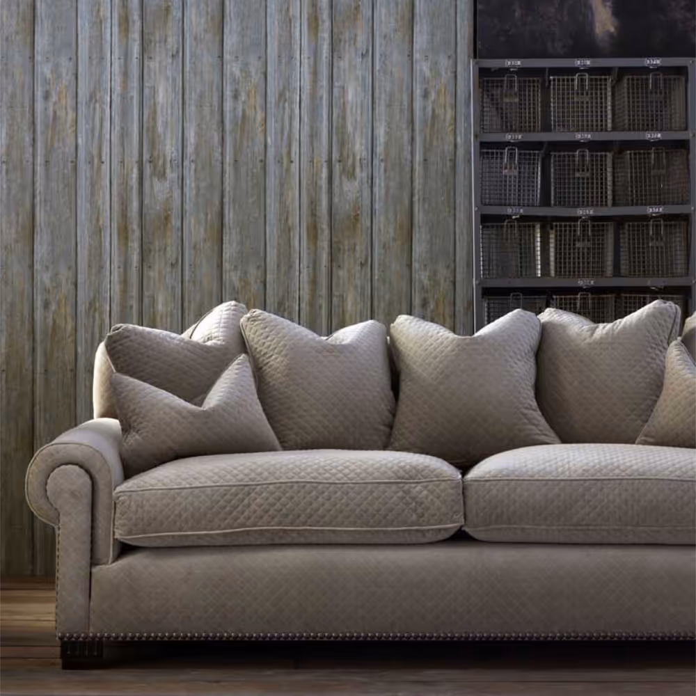 A comfy cream sofa in front of a wall with a timber panel effect wallpaper