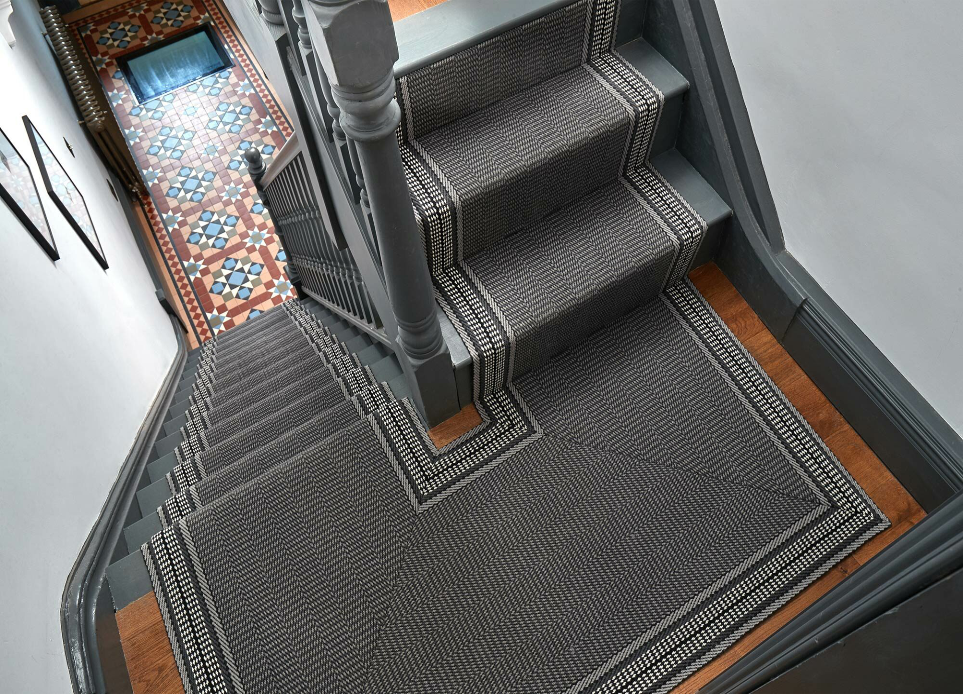 A grey and black stair runner on a half landing