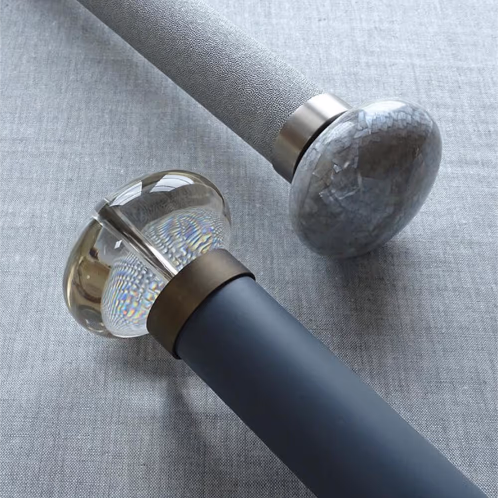Two fabric wrapped curtain poles with glass finials.