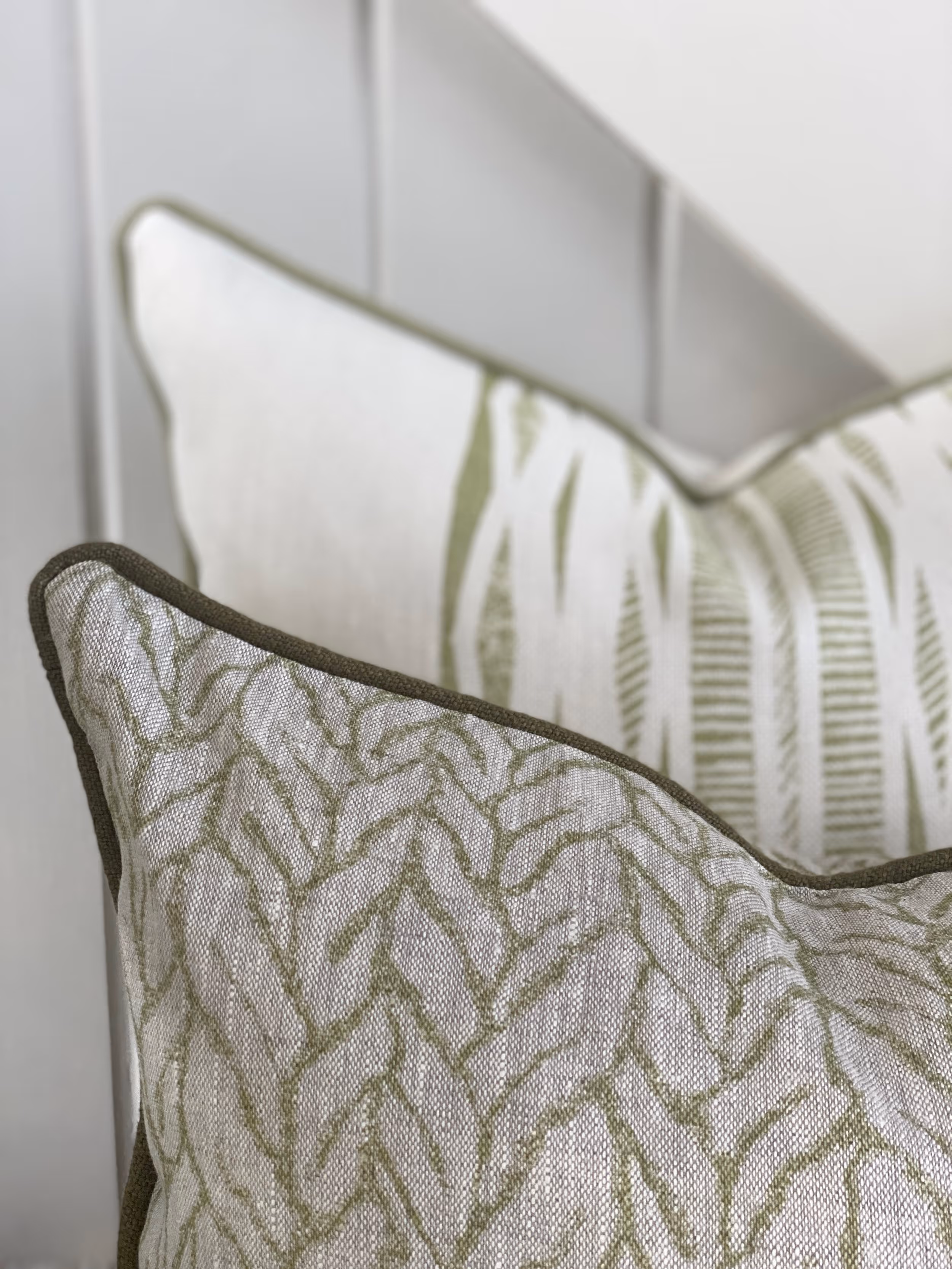 Two cushions made from printed linen fabric in olive green on a natural ground.